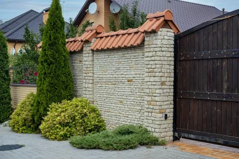 Modern brick pattern of light stone fence wall with tiles in front of a resid Stock Photos