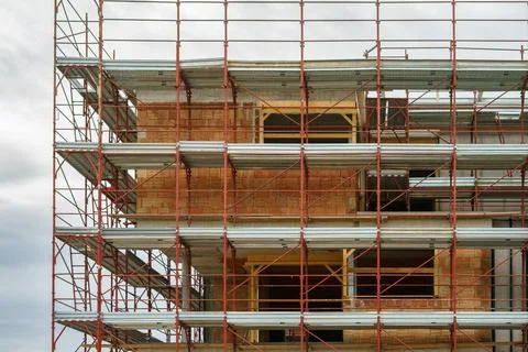 Modern brick structure surrounded by scaffolding on an active construction si Stock Photos
