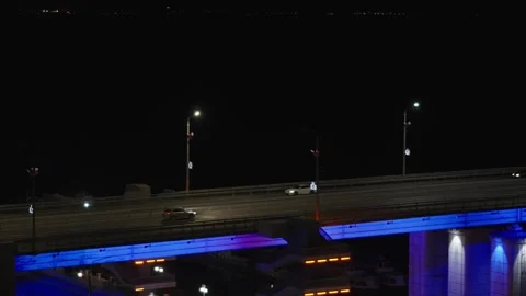 A modern bridge at night featuring bright blue neon under-lighting, street la Stock Footage 345020022