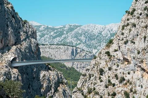 Modern bridge spanning a dramatic rocky canyon under a clear blue sky Stock Photos