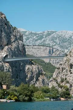 Modern bridge spans a dramatic canyon with lush greenery and blue sky Stock Photos