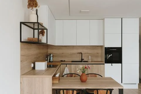 Modern bright kitchen interior with white furniture and wooden dining table Stock Photos