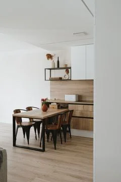 Modern bright kitchen interior with white furniture and wooden dining table Stock Photos