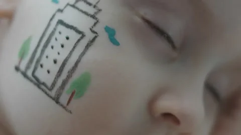 Modern building drawing on the face of a cute little girl. Laying with closed Stock Footage 256042826