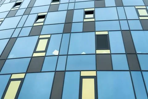 Modern building facade with blue and yellow glass windows in geometric grid.. Stock Photos