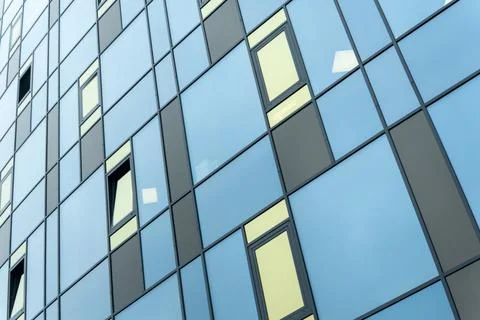 Modern building facade with blue and yellow glass windows in geometric grid.. Stock Photos