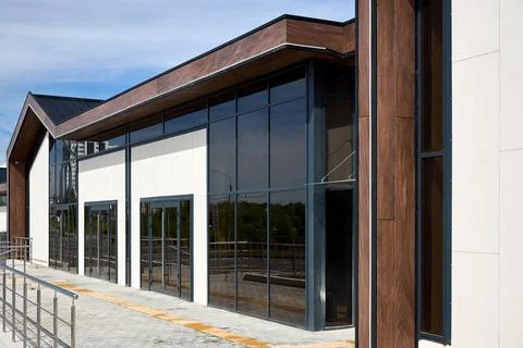 Modern building facade features large glass windows, dark metal frames, and.. 스톡 사진