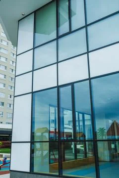 Modern building with large windows showing reflections of nearby structures.. Stock Photos