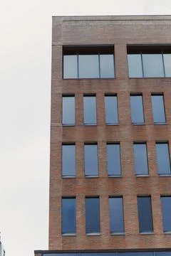 Modern building with multiple windows in an urban setting during cloudy weath Photos