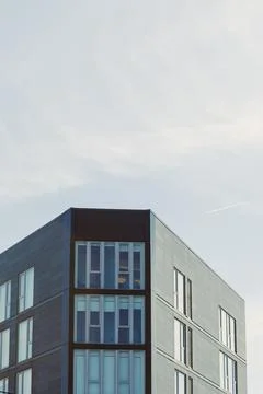 Modern building structure under clear sky with faint airplane trail visible.. Stock Photos