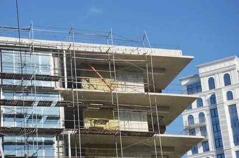 Modern building under construction with scaffolding against blue sky. 写真素材