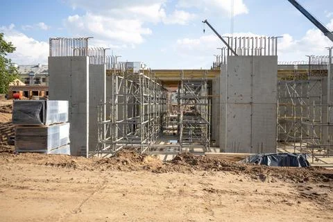 Modern building under construction. Workers set up scaffolding and formwork f Stock Photos