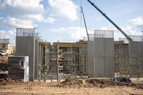 Modern building under construction. Workers set up scaffolding and formwork f Stockfoto's