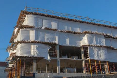 Modern Building Under Construction Wrapped in Protective Sheets Stock Photos