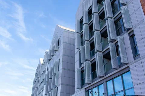 Modern building with unique design under clear sky in urban area Stock Photos