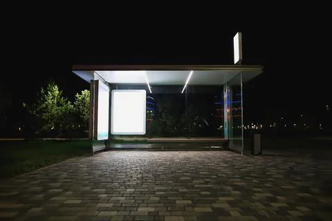 Modern bus stop with an empty billboard at night Stock Photos