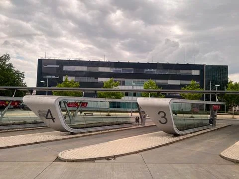 Modern bus stop shelters in front of office building under cloudy sky Stock Photos