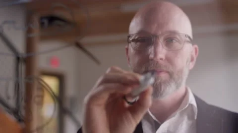 Modern businessman brainstorms while writing on plexiglass with a marker Video stock 133269876