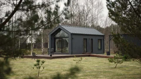 Modern cabin with dark cladding and glass frontage among pines Stock Footage 337264676