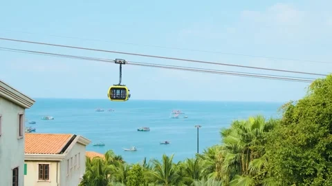 Modern cable car cabin ride over tropical seaside with fishing boats and blue Stock Footage 312813666