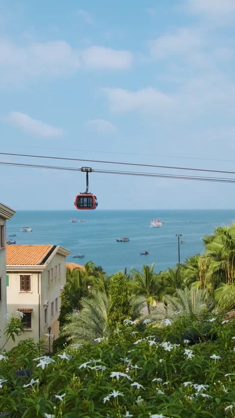 Modern cable car cabin ride over tropical seaside with fishing boats and blue Video stock 322070337