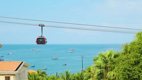 Modern cable car gondola ride over tropical seaside with fishing boats and blue Stock Footage 312813625