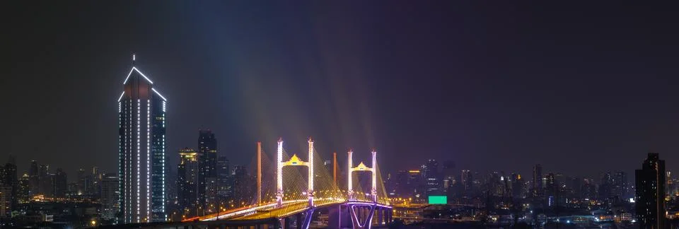 Modern Cable Stayed Bridge Illuminated At Night With Skyscraper Skyline Pan.. Foto stock