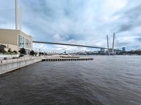 Modern cable-stayed bridge over cloudy urban waterfront scene Stock Photos