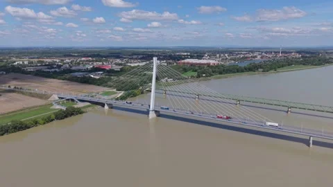 A modern cable-stayed bridge spans a wide, muddy river, connecting two banks Stock Footage 314695943