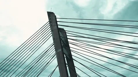 Modern cable-stayed bridge structure with steel tension cables converging toward Stock Footage 320250243