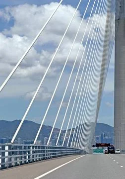 Modern cable stayed bridge structure with city skyline and mountains in the.. Stock Photos