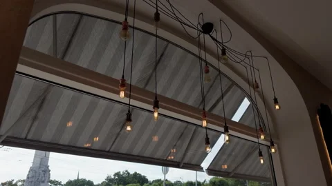 Modern cafe ceiling with hanging Edison bulbs beside arched window and warm Stock Footage 344966866
