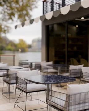 A modern cafe or restaurant features an outdoor patio area with rows of tab.. Illustrazione stock