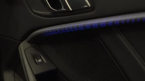 Modern car interior door panel featuring a vibrant blue LED ambient lighting Stock Footage 336659643