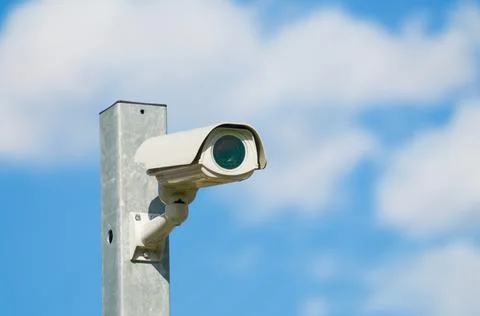 Modern CCTV camera on a iron pole against blue sky Stock Photos