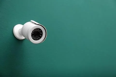 Modern CCTV security camera on green wall. Space for text Stock Photos