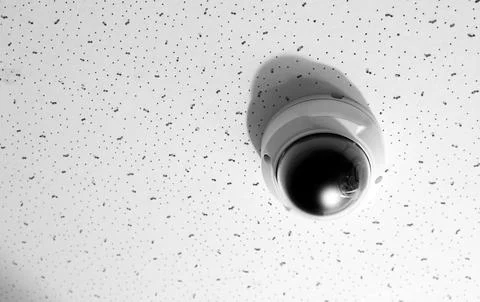 Modern CCTV security camera on white ceiling. Space for text Stock Photos