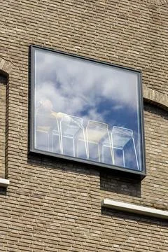 Modern chairs behind large reflective window on brick building facade Stock Photos