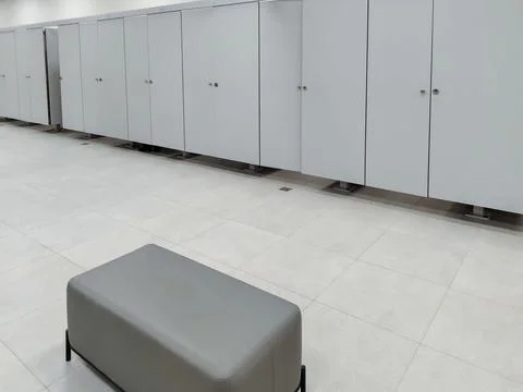 Modern changing room interior featuring gray lockers and a padded bench on .. Fotos de archivo