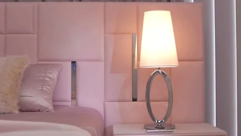 Modern chrome bedside lamp in a luxurious bedroom by a stylish bed Stock Footage 159806936