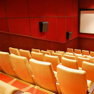 Modern cinema hall empty and beige comfortable seats, white cinema screen Stock Photos