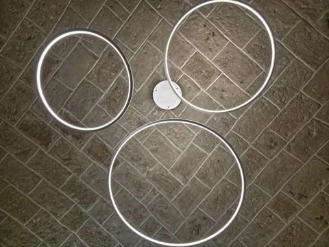 Modern circular LED ceiling lights on stone wall background minimalist design Stock Photos