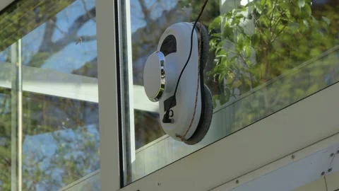 Modern cleaning robot for glass surfaces operates on a residential window. Stock Footage 336842553
