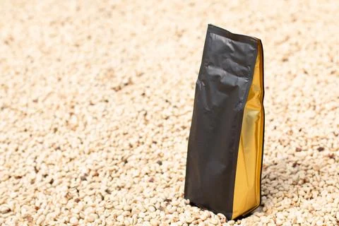 Modern coffee bag packaging on drying coffee beans. Black coffee bag with gold Stock Photos