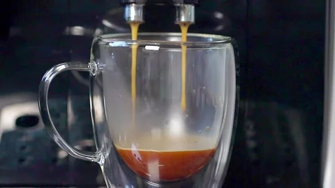 A modern coffee machine pours delicious coffee into a transparent cup standing  Stock Footage 261688687
