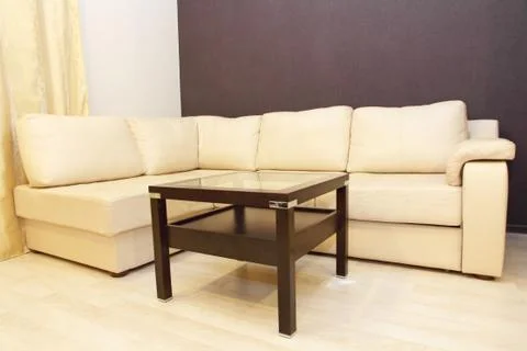 Modern comfortable white corner leather sofa and coffee table. Stock Photos