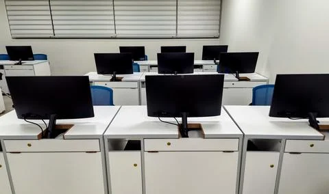Modern computer classroom with rows of monitors and white desks Stock Photos