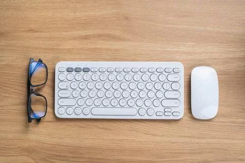 Modern Computer Keyboard and Mouse on Wooden Desk with Stylish Eyeglasses, .. Stock Photos