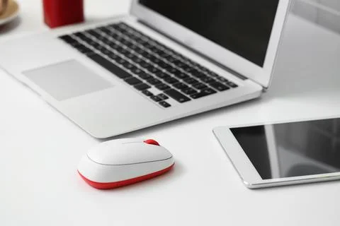 Modern computer mouse with laptop and tablet computer on table in office Stock Photos
