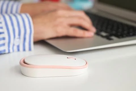Modern computer mouse on table of woman working with laptop in office Stock Photos